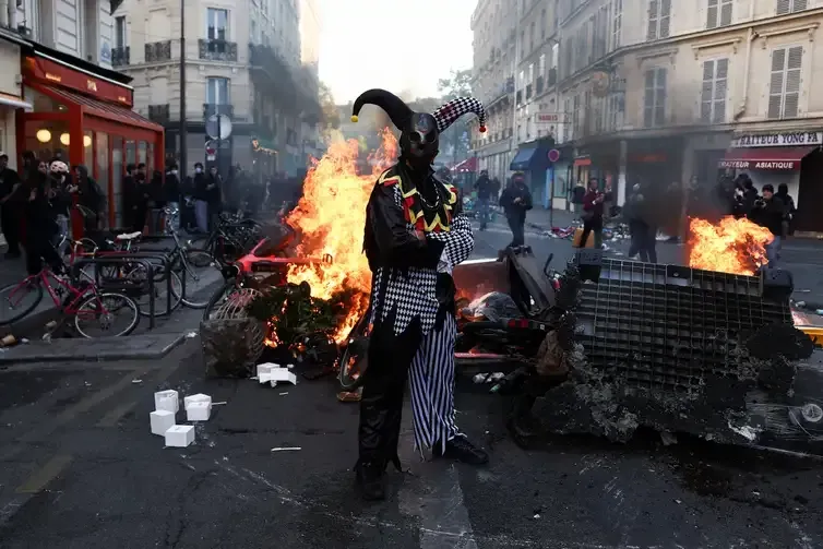 REUTERS/Abdul Saboor/Proibida reprodução A demonstrator wearing a costume stands in front of burning flames, in Paris, France, October 18, 2026. REUTERS/Abdul Saboor