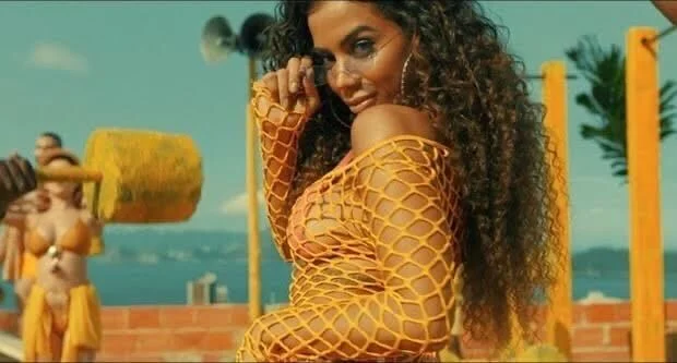 Já em 2019, as acusações de apropriação cultural voltaram quando ela lançou o clipe "Muito Calor", no qual aparecia com as madeixas cacheadas. Ela rebateu os comentários e publicou  fotos dela criança, destacando que os fios já eram cacheados desde a infância. Reprodução YouTube