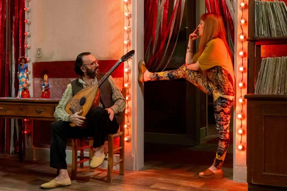 Enquanto o libanês toca o alaúde, Iolanda chega reclamando da zorra que estão fazendo na sua casa Divulgação/Globo