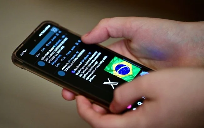 Um usuário brasileiro da rede social X, o antigo Twitter, navega por postagens em um celular em Brasília, em 31 de agosto de 2024 Um usuário brasileiro da rede social X, o antigo Twitter, navega por postagens em um celular em Brasília, em 31 de agosto de 2024