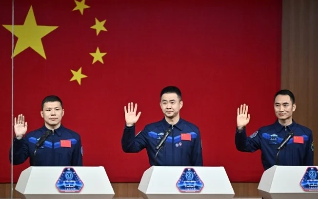 A tripulação da missão Shenzhou-20 (da esquerda para a direita, Wang Jie, Chen Dong e Chen Zhongrui) acena durante uma coletiva de imprensa no Centro de Lançamento Espacial de Jiuquan, no noroeste da China, em 23 de abril de 2025 A tripulação da missão Shenzhou-20 (da esquerda para a direita, Wang Jie, Chen Dong e Chen Zhongrui) acena durante uma coletiva de imprensa no Centro de Lançamento Espacial de Jiuquan, no noroeste da China, em 23 de abril de 2025