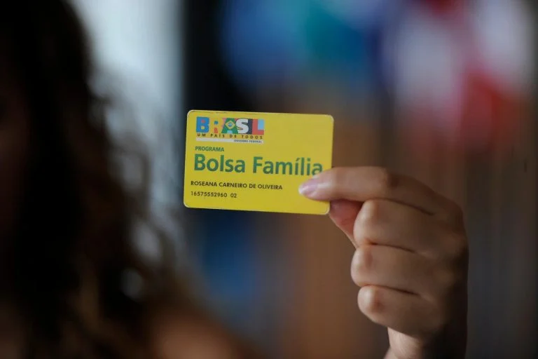 Mulher segura um cartão do Bolsa Família