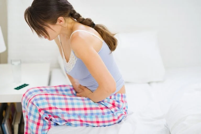 Mulher com cólica sentada na cama