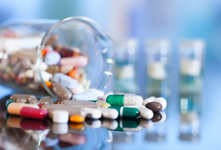 Medicamentos – comprimidos, drágeas e pílulas – misturados e espalhados em cima de uma superfície espelhada
