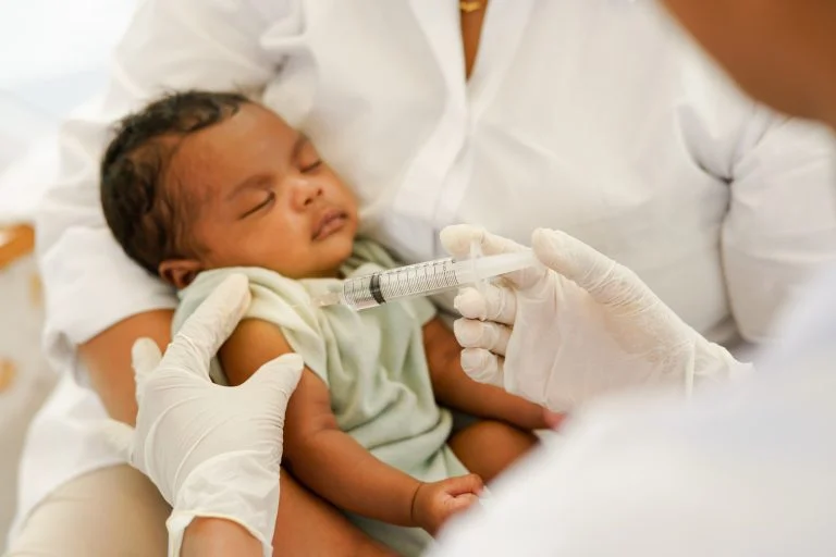 Close up da mão do médico segurando a seringa para vacinar o bebê recém-nascido