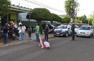 Alunos de escola estadual atravessam rua, policial militar mulher ajuda na travessia