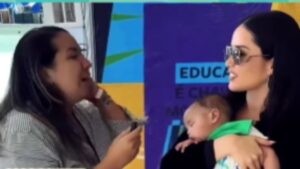 Juliette segura bebê de repórter no colo durante entrevista