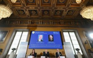 Os dois ganhadores dos prêmios Nobel de Física, o britânico-canadense  Geoffrey Hinton e o americano John Hopfield, aparecem em um telão depois do anúncio do prêmio em Estocolmo, em 8 de outubro de 2024