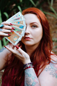 Mulher ruiva segurando cartas de tarot