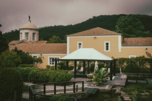 Foto mostra as instalações do spa do hotel: um edificio amarelo, com uma torre de igreja ao fundo e a montanha verdejante ao fundo